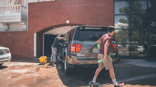 Two Men Washing And Waxing A Car In The Sun